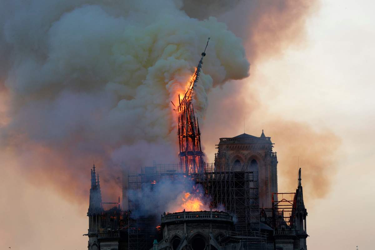 The steeple engulfed in flames collapses as the roof of the Notre-Dame de Paris Cathedral burns on April 15, 2019 in Paris.