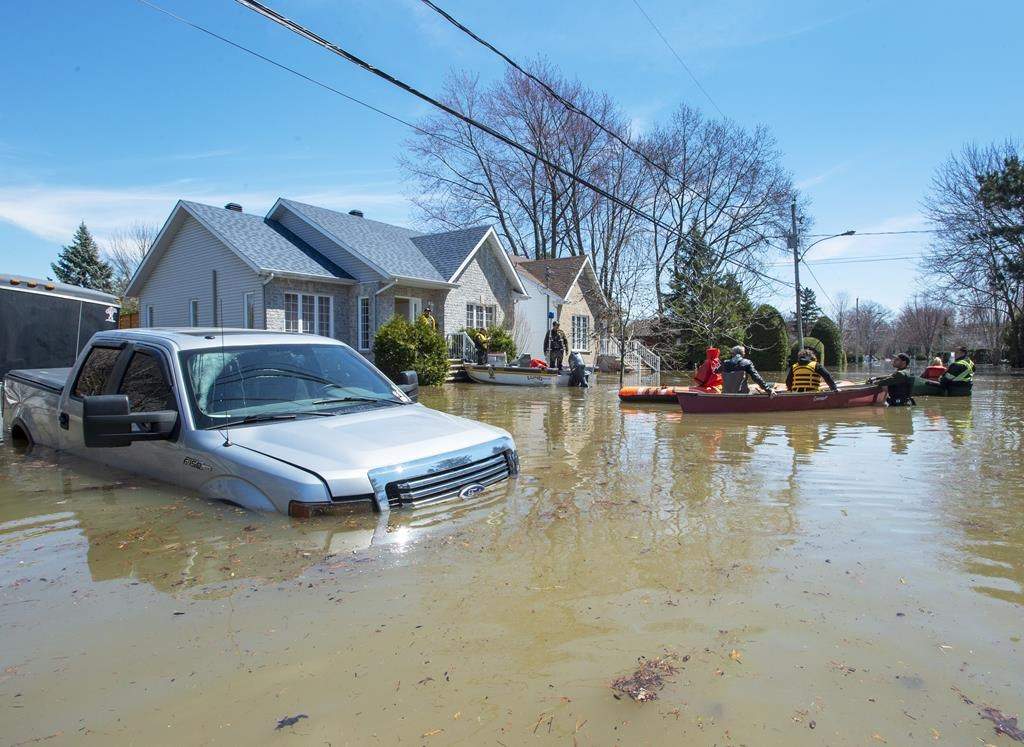 Quebec Provincial Police officers escort evacuees to retrieve belongings from their flooded homes on Monday, April 29, 2019 in Ste.Marthe-sur-la-Lac, Que.