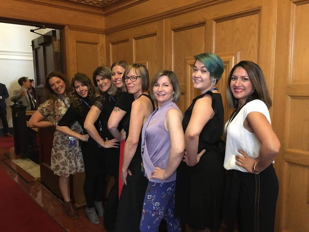 Bhinder Sajan, right to left, Shannon Waters, Liza Yuzda, Justine Hunter, Jen Holmwood, Katie DeRosa, Tanya Fletcher and Kylie Stanton pose for a photo at the B.C. Legislature in Victoria on March 28, 2019. The Speaker of B.C.\’s legislature says a preliminary review of the building\’s dress code now permits women to wear sleeveless dresses and sleeveless shirts.
