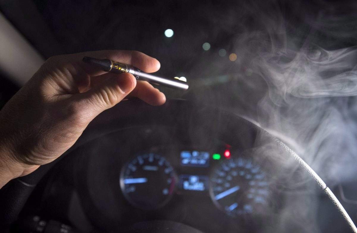 In this photo illustration, smoke from a cannabis oil vaporizer is seen as the driver is behind the wheel of a car in North Vancouver, B.C.