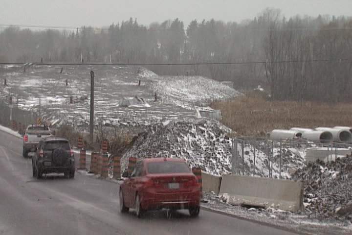 Tons of crushed rock on the site of John Counter Boulevard’s future rail overpass needs years to settle before bridge deck work can start.