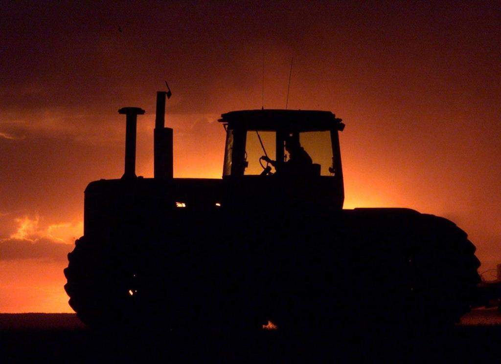 A farm tractor is silhouetted against a setting sun near Mossbank, Sask., Saturday May 11, 2002.