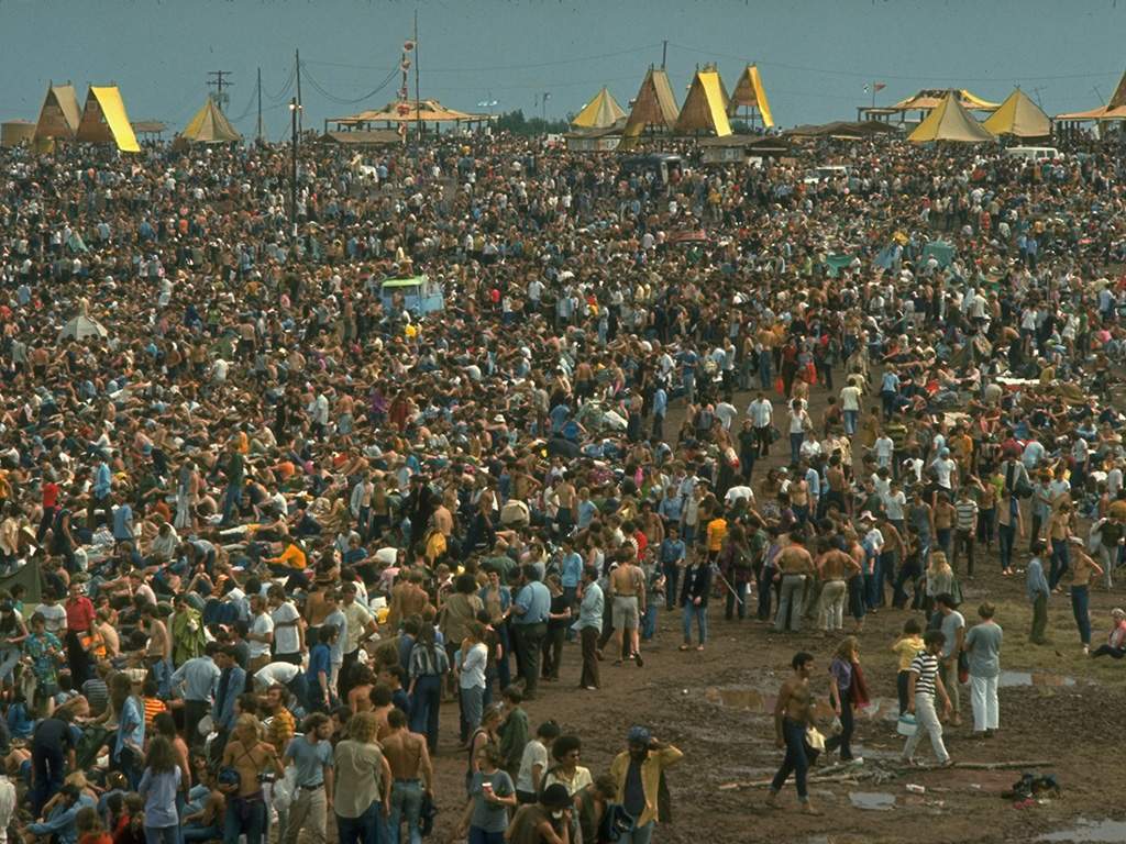 A huge crowd looking towards the large yellow tents during the Woodstock Music and Art Fair in 1969.