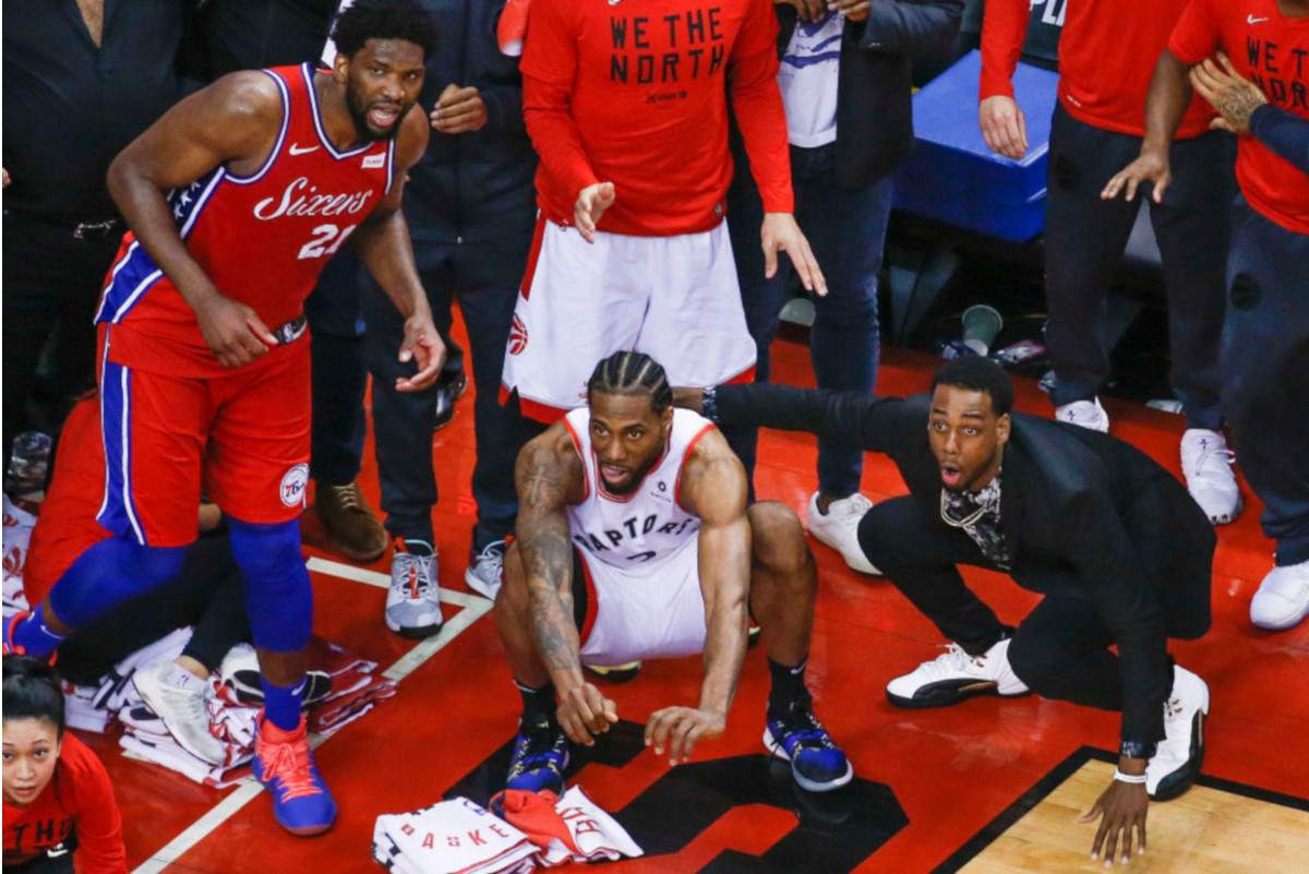 Philadelphia 76ers center Joel Embiid watches from the corner as Toronto Raptors forward Kawhi Leonard squats down and sticks out his tongue waiting for the ball to drop for Raptors to win.