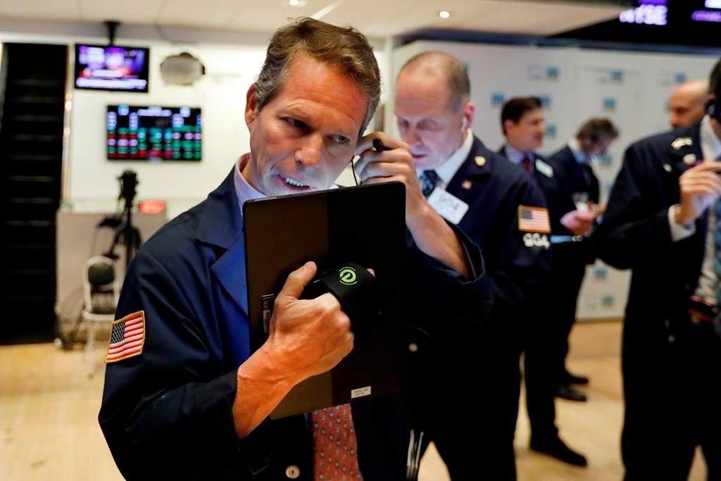 FILE - In this May 1, 2019, file photo, trader Robert Charmak, left, works on the floor of the New York Stock Exchange.