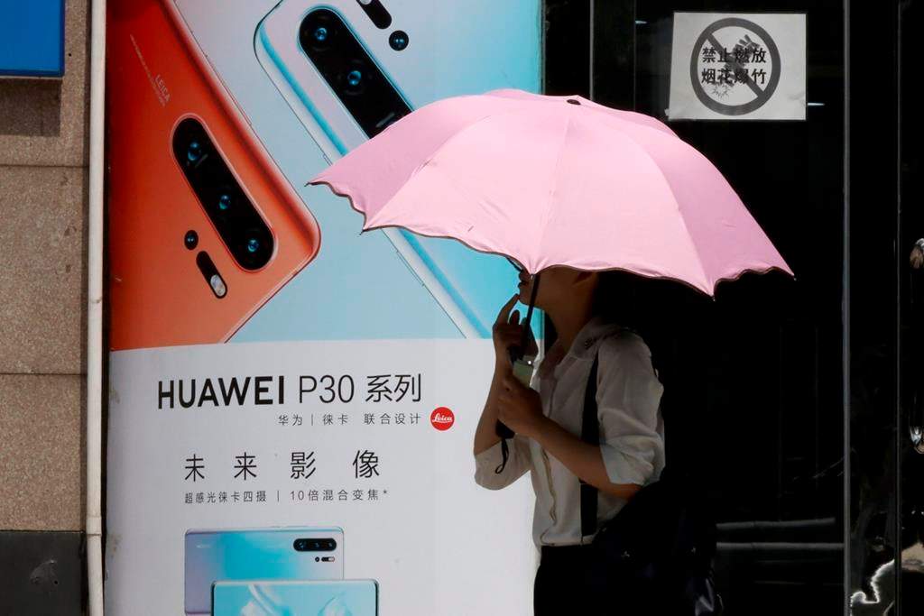 A woman walks past advertisement for Huawei smartphones in Beijing on Thursday, May 16, 2019. In a fateful swipe at telecommunications giant Huawei, the Trump administration issued an executive order Wednesday apparently aimed at banning its equipment from U.S. networks and said it was subjecting the Chinese company to strict export controls.