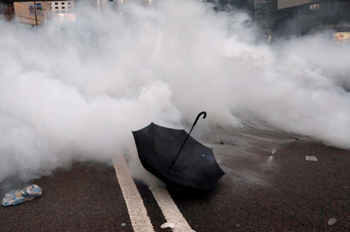 An umbrella lies on the ground as tear gas is seen during a demonstration against a proposed extradition bill in Hong Kong, China on June 12, 2019. REUTERS/Tyrone Siu