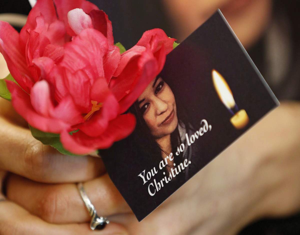 A woman holds a flower and a photo of Christine Wood during a vigil in Winnipeg, Wednesday, April 12, 2017.