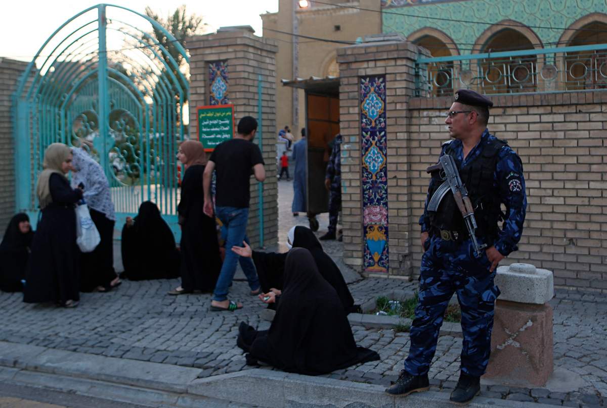 Security forces stand guard outside the 17th of Ramadan mosque as Muslims gather for prayers on the first day of Eid al-Fitr in Baghdad, Iraq, Tuesday, June 4, 2019.