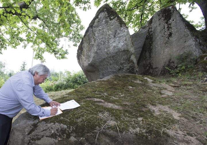 Chief Dalton Silver signs a letter to the government of British Columbia at the foot of Lightning Rock following a ceremony of Indigenous leaders in a call to save a First Nations burial site in Abbotsford, B.C., Friday, June 14, 2019.