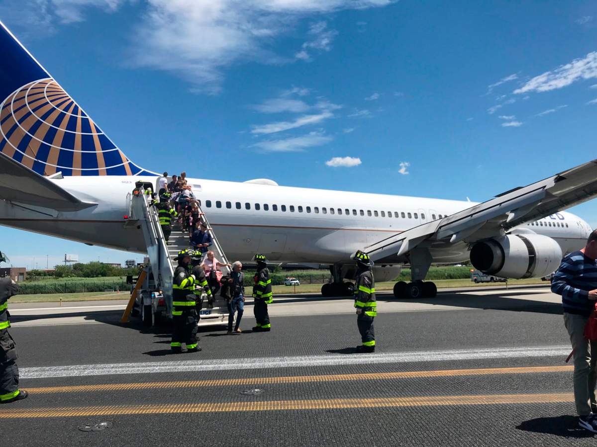 This photo provided by Caroline Craddock shows emergency personnel help passengers off a plane after a United Airlines plane skidded off the runway after landing at Newark Liberty International Airport on Saturday, June 15, 2019 in Newark, N.J.
