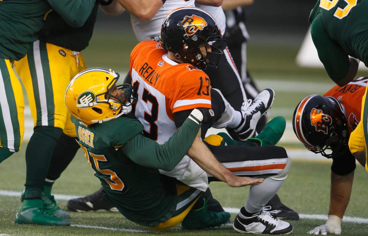B.C. Lions quarterback Mike Reilly (13) is sacked by Edmonton Eskimos Nick Usher (75) during second half CFL action in Edmonton, Alta., on Friday June 21, 2019. 