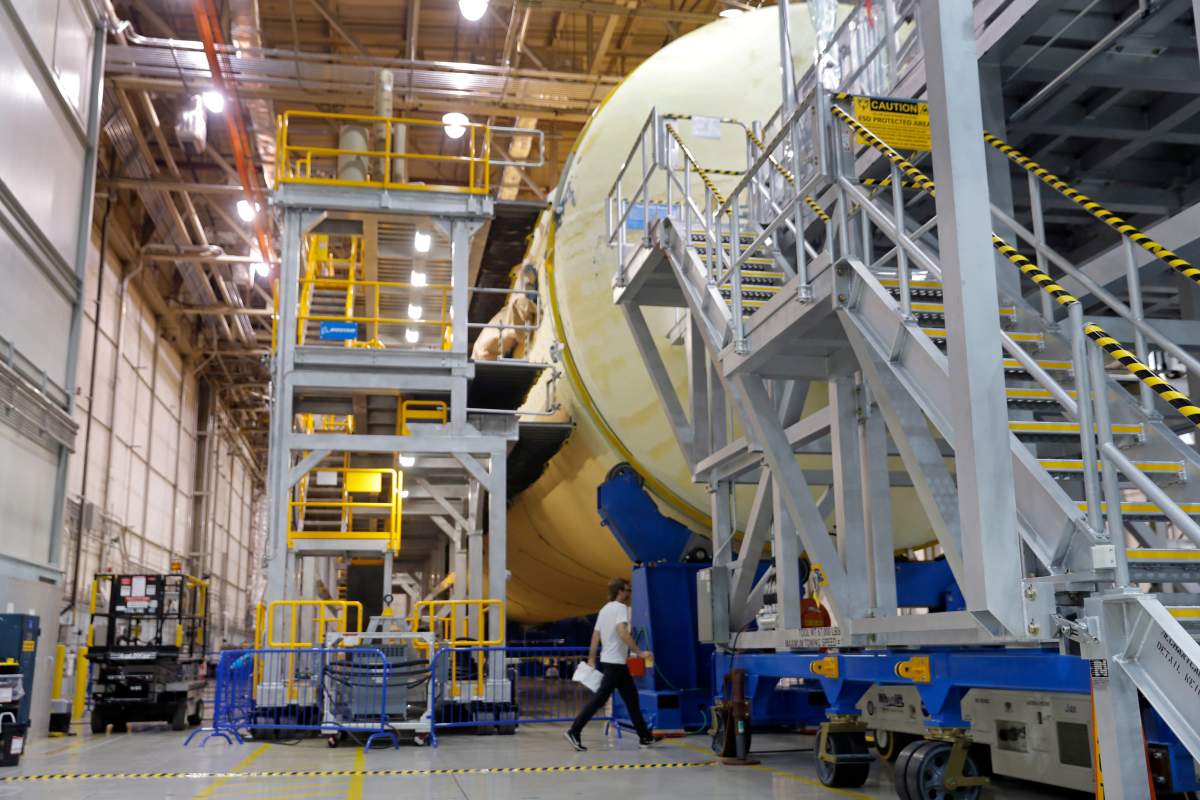 A man walks underneath the core stage for NASA's Space Launch System (SLS), which they say will carry the Orion spacecraft, and ultimately a crew, to the moon and beyond, at the NASA Michoud Assembly Facility in New Orleans, Friday, June 28, 2019. ().