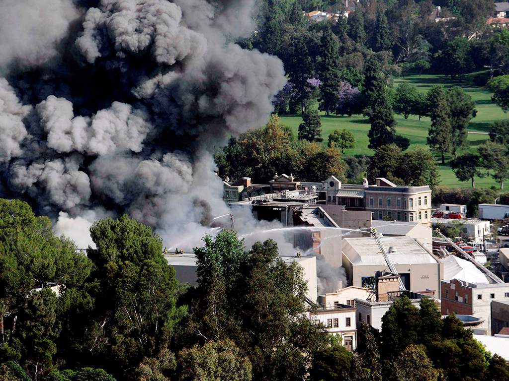 Firefighters on ladders pour water on a large fire burning on the back lot of Universal City Studios in Universal City, Los Angeles, Calif. on Sunday, June 1, 2008. 