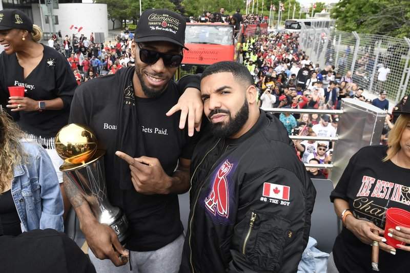 Toronto Raptors forward Kawhi Leonard points at his playoffs MVP trophy as he poses with performing artist Drake during the 2019 Toronto Raptors NBA basketball championship parade in Toronto, Monday, June 17, 2019.
