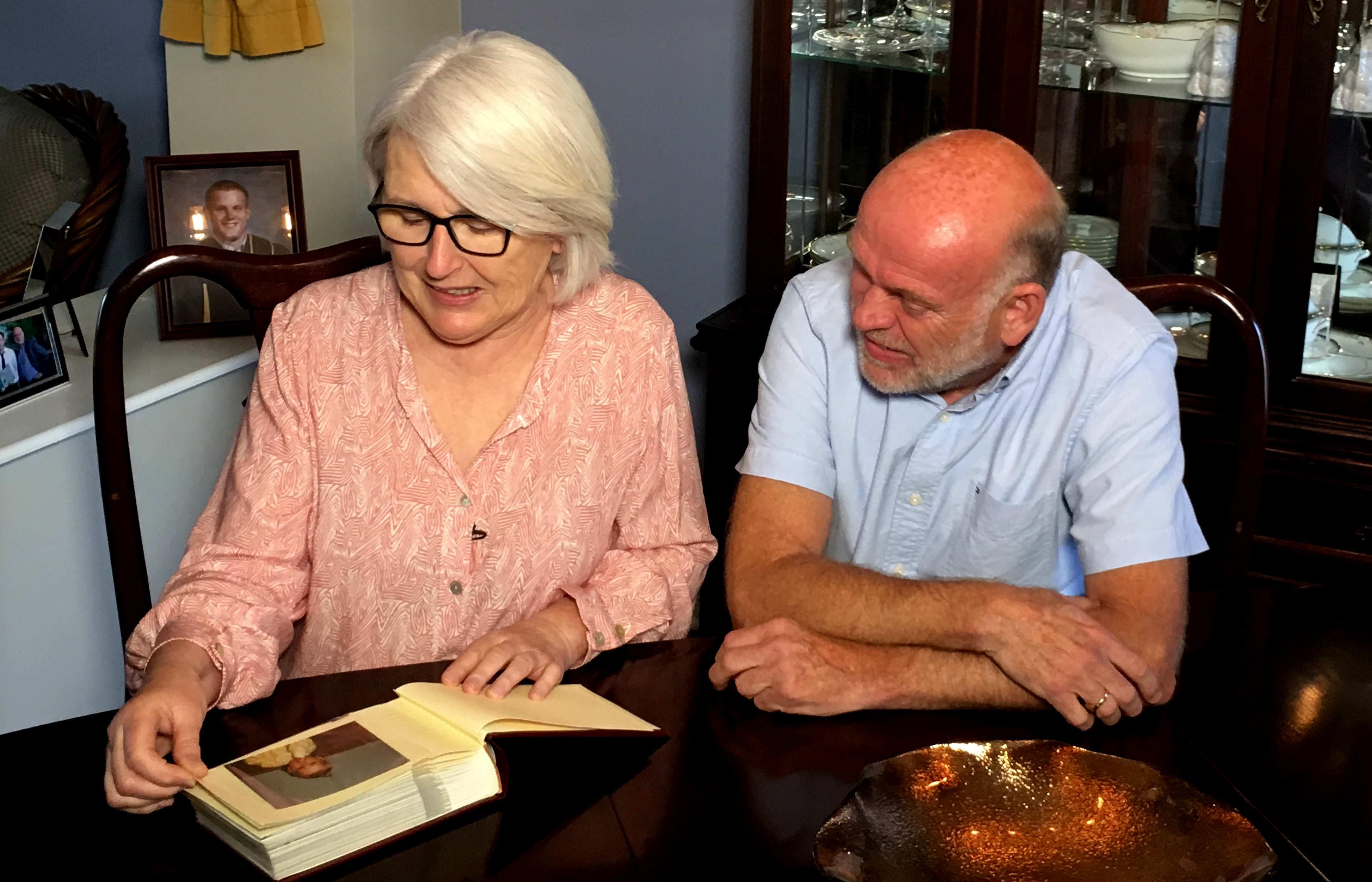 Jill Broadbent and her husband Derek Fudge look at a photo album in their home near Ottawa.