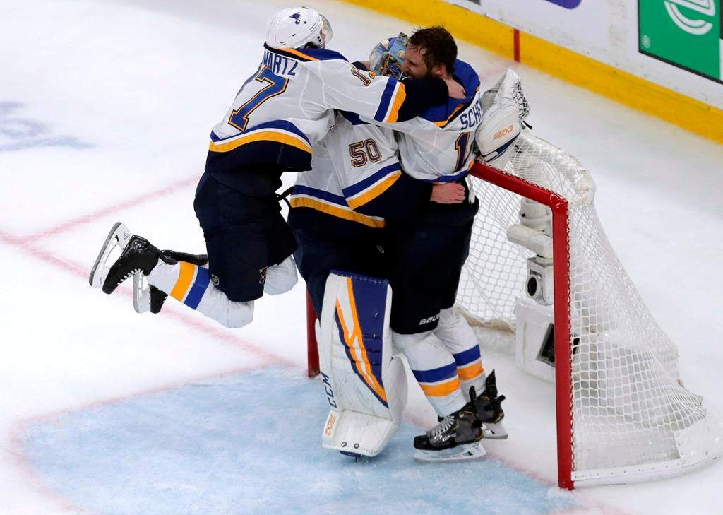 St. Louis Blues' Jaden Schwartz, left, and Brayden Schenn, right, mob goaltender Jordan Binnington to celebrate their win over the Boston Bruins in Game 7 of the NHL hockey Stanley Cup final, Wednesday, June 12, 2019, in Boston.