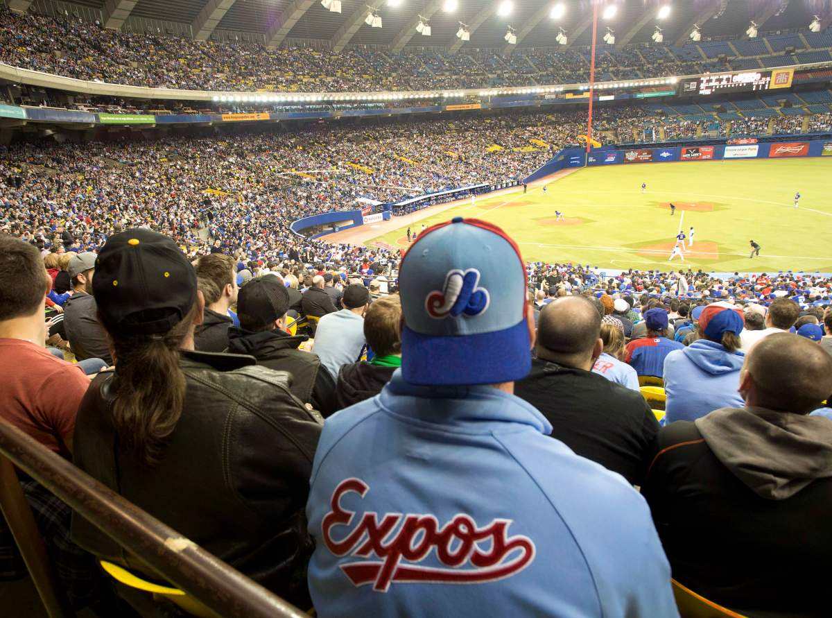 Fans wear Montreal Expos uniforms as they watch the Toronto Blue Jays in a pre-season baseball game against the New York Mets on Friday, March 28, 2014 in Montreal.