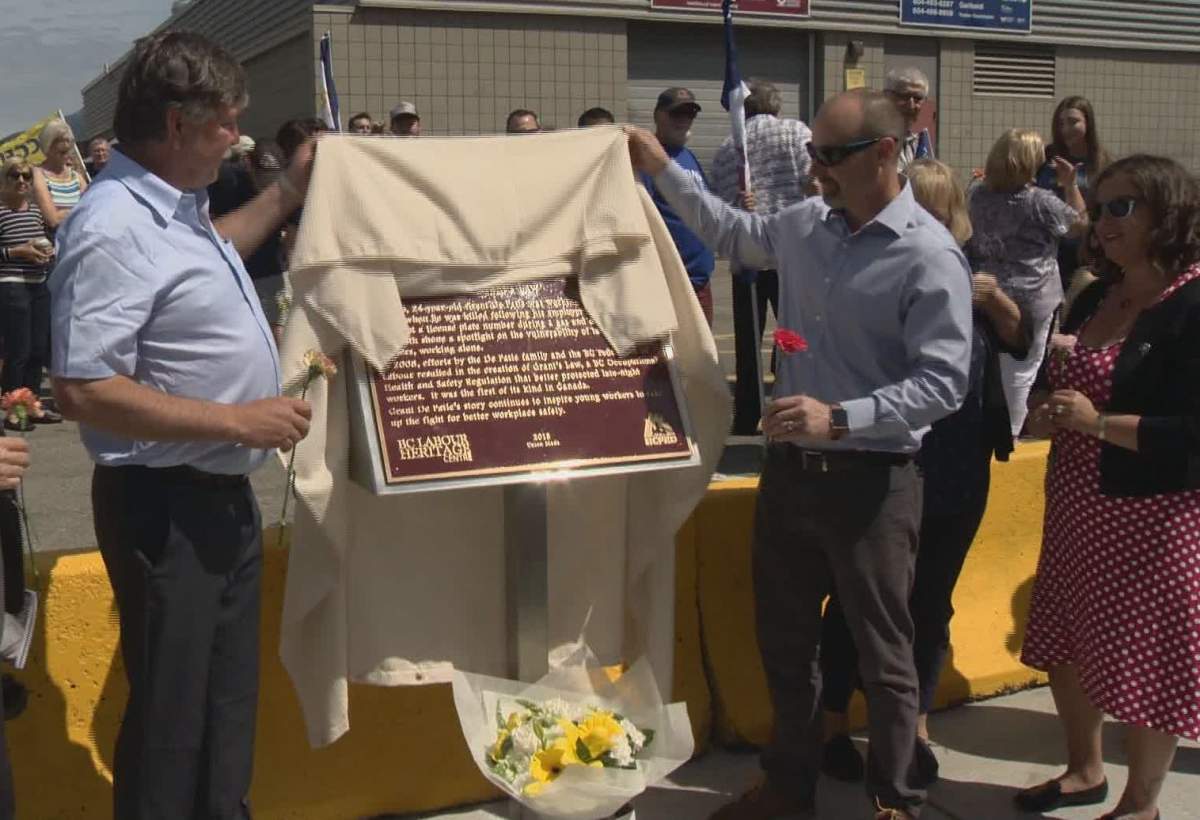 Doug De Patie, left, helps unveil a plaque dedicated to his son Grant outside Garibaldi Secondary School in Maple Ridge on Saturday, June 1, 2019. Grant was killed in March 2005 during an incident at the gas station he worked at that prompted new protections for late-night workers.