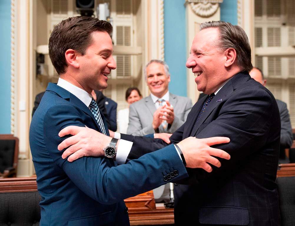 Quebec Minister of Immigration, Diversity and Inclusiveness Simon Jolin Barrette, left, is congratulated by Quebec Premier Francois Legault.
