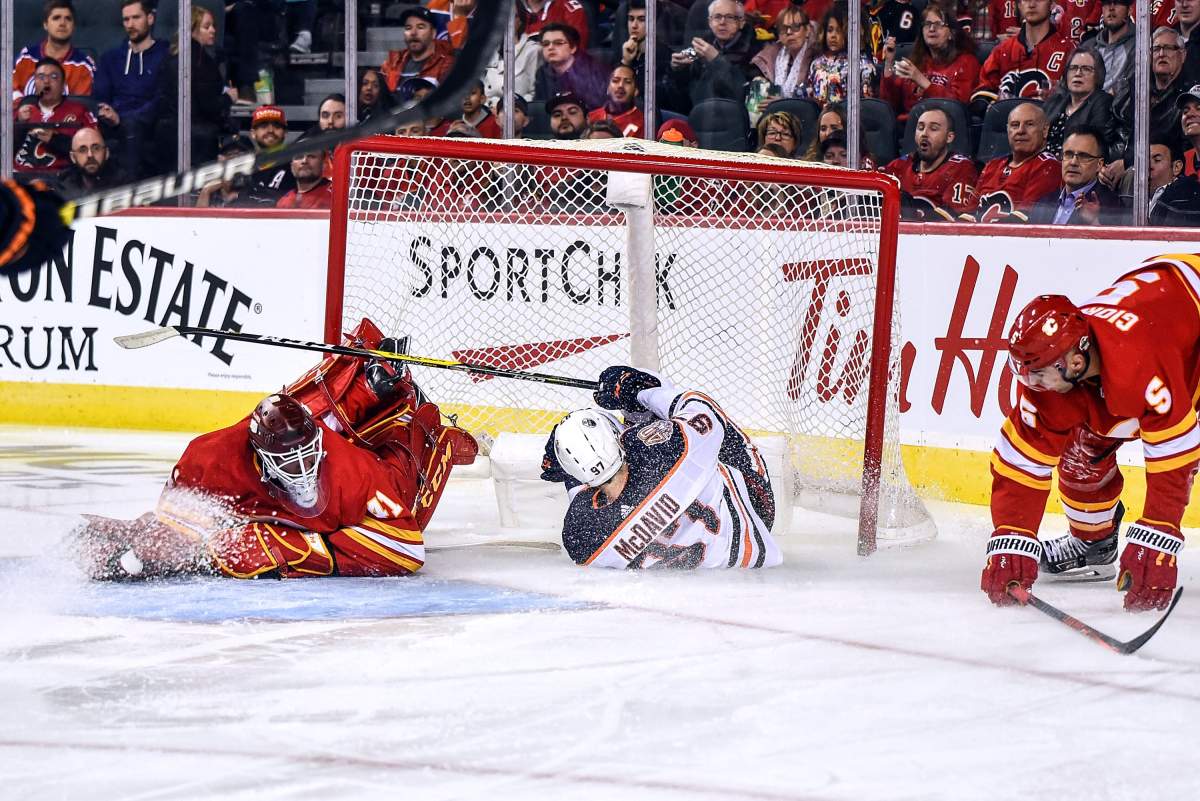 Edmonton Oilers Center Connor McDavid crashes into Calgary Flames Goalie Mike Smith (41) and the net during the second period of an NHL game where the Calgary Flames hosted the Edmonton Oilers on April 6, 2019, at the Scotiabank Saddledome in Calgary, AB.