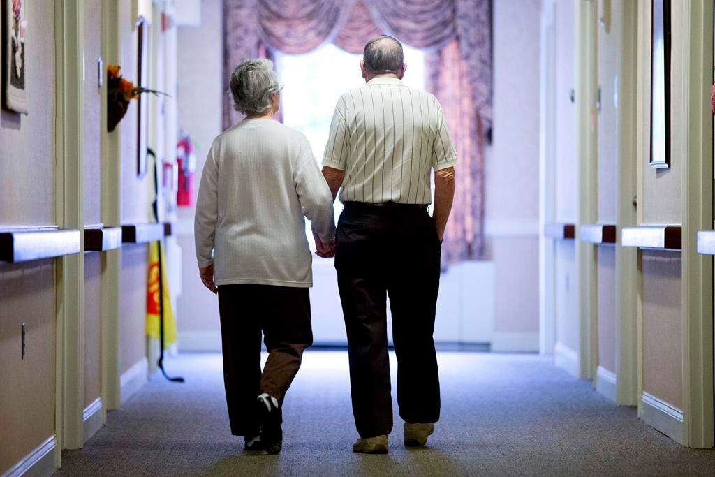 FILE - In this Nov. 6, 2015 file photo, an elderly couple walk down a hall of a nursing home in Easton, Pa.