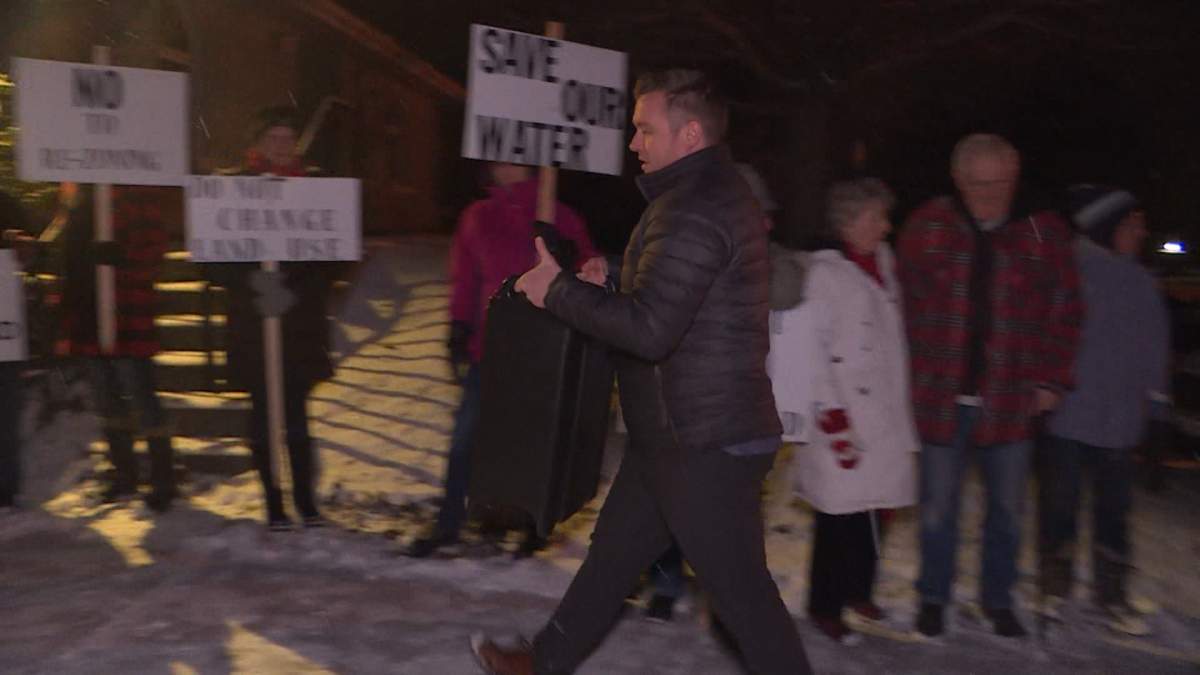Developer Ben Pilon passes by protesters on his way into a meeting with residents last year.