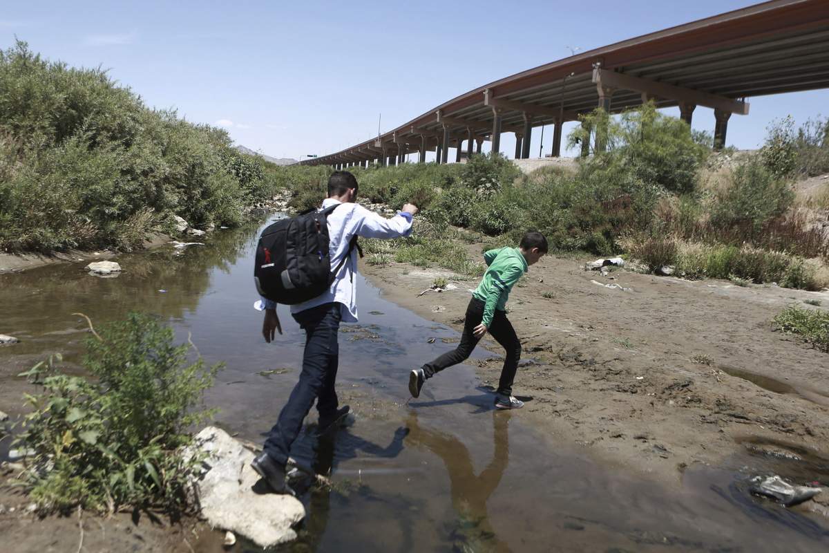 In this June 7, 2019, file photo, people cross the Rio Grande into the United States to turn themselves over to authorities and ask for asylum, as seen from Ciudad Juarez, Chihuahua, Mexico, opposite El Paso, Texas.