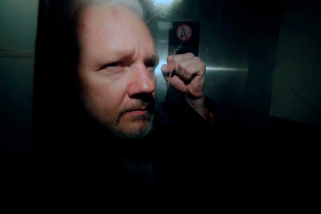 In this May 1, 2019, file photo, WikiLeaks founder Julian Assange puts his fist up as he is taken from court in London. The Justice Department has charged Assange with receiving and publishing classified information.
