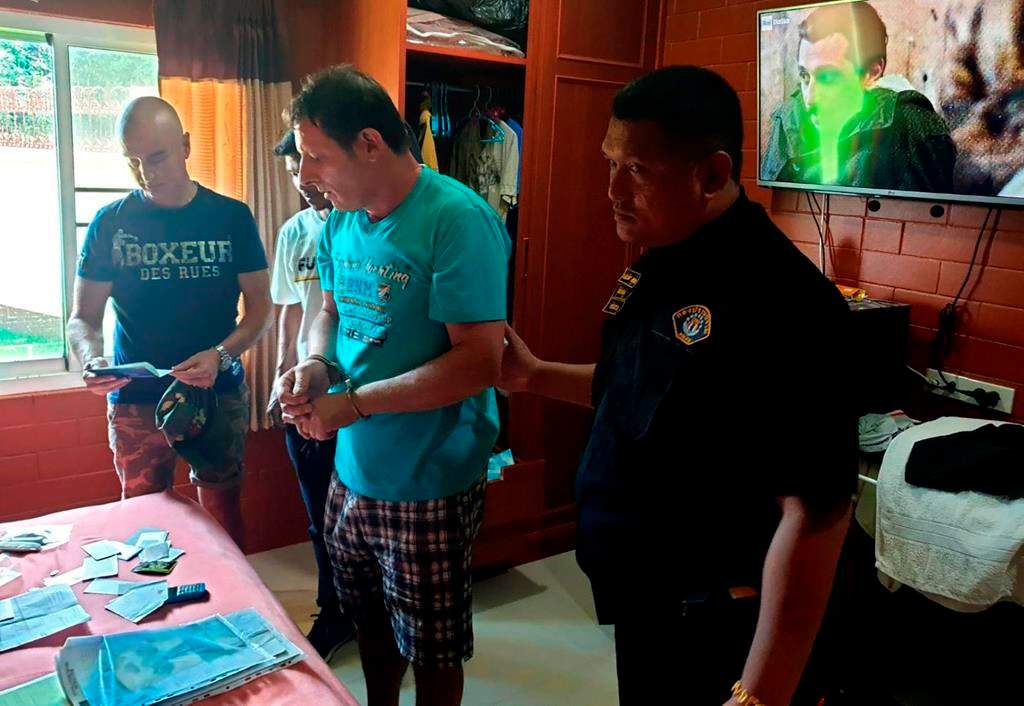 In this June 15, 2019, photo released by Crime Suppression Division, Italian Francesco Galdeli, centre, is arrested by Thai police officers at a house in Chonburi.  (Crime Suppression Division of Thailand via AP)