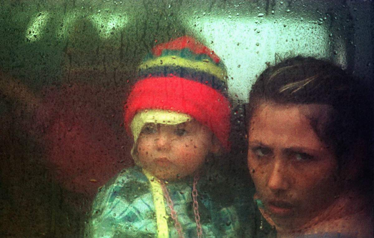 FILE – In this Friday, May 7, 1999 file photo, an ethnic Albanian mother and child bound for Canada leave for the airport from the Stenkovec refugee camp outside Skopje, Macedonia. They are among hundreds of thousands of refugees who fled Serbian forces in Kosovo in the previous month. Canada airlifted more than 5,000 people from Kosovo in the late 1990s.