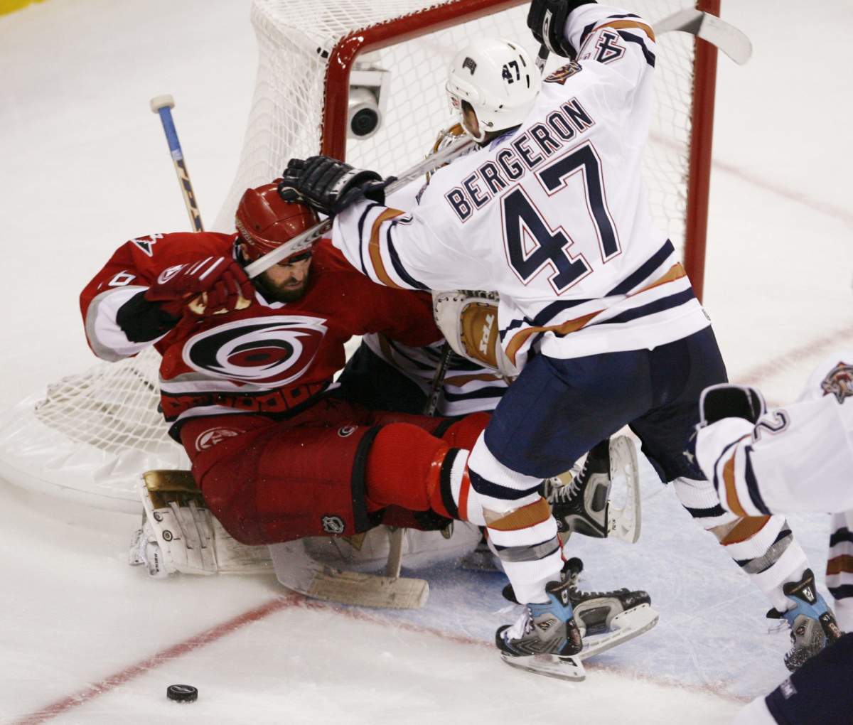 Edmonton Oilers Marc-Andre Bergeron right, pushes Carolina Hurricanes Andrew Ladd into goalie Dwayne Roloson during third period of the first game of NHL Stanley Cup final in Raleigh, NC Monday June 5, 2006. Carolina won 5-4.
