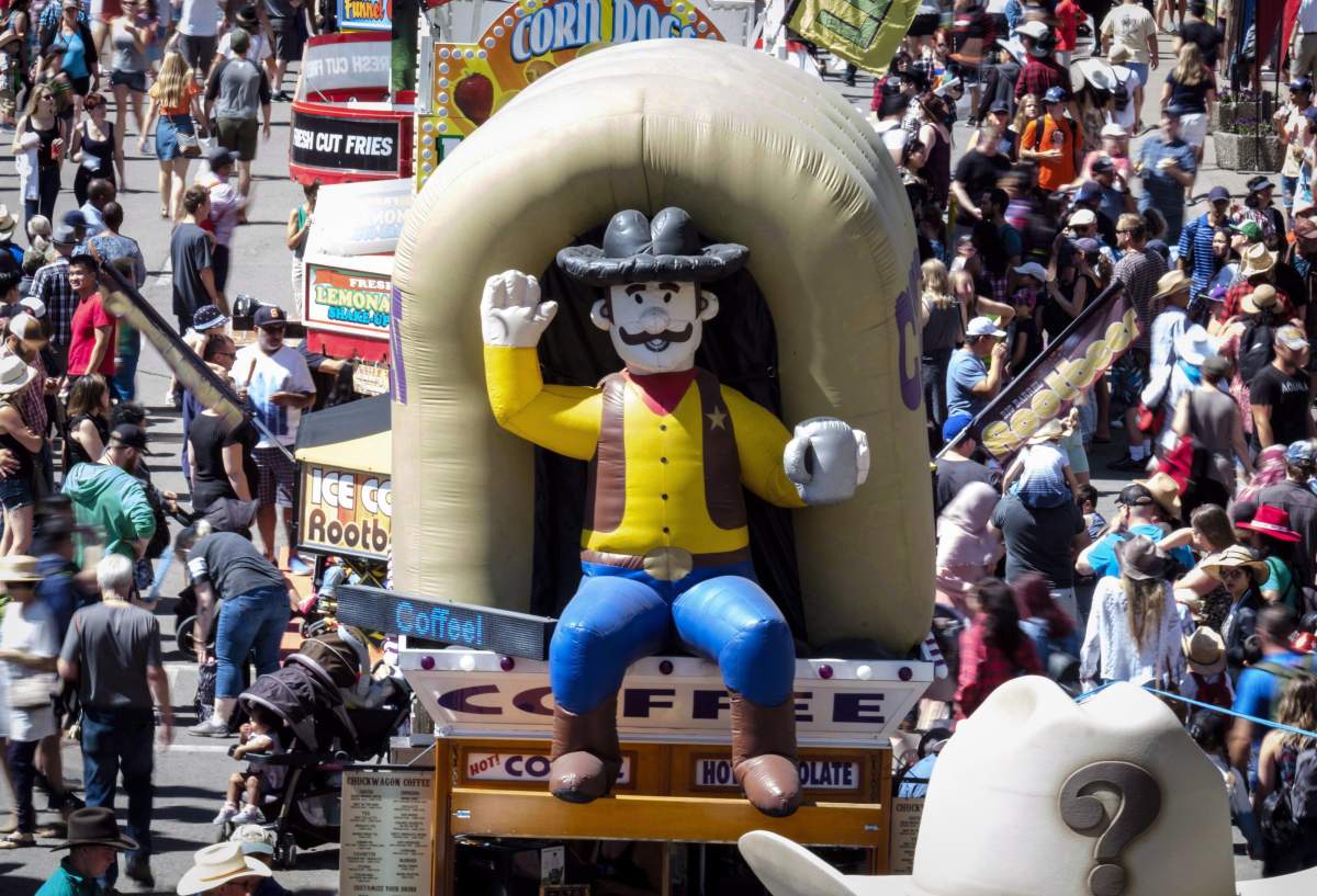 FILE - Crowds walk along the midway during the Calgary Stampede in Calgary on July 8, 2018.
