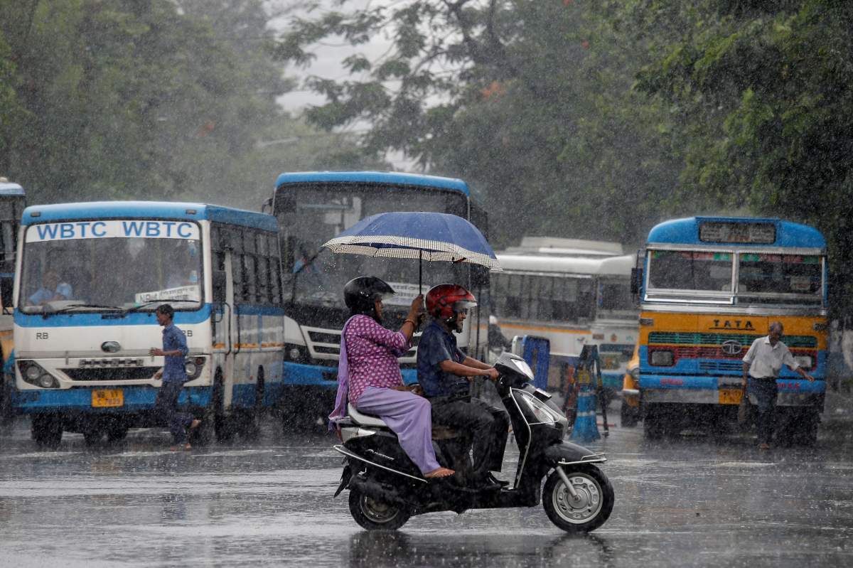 People ride a scooter through a road as it rains in Kolkata, India, July 2, 2019.