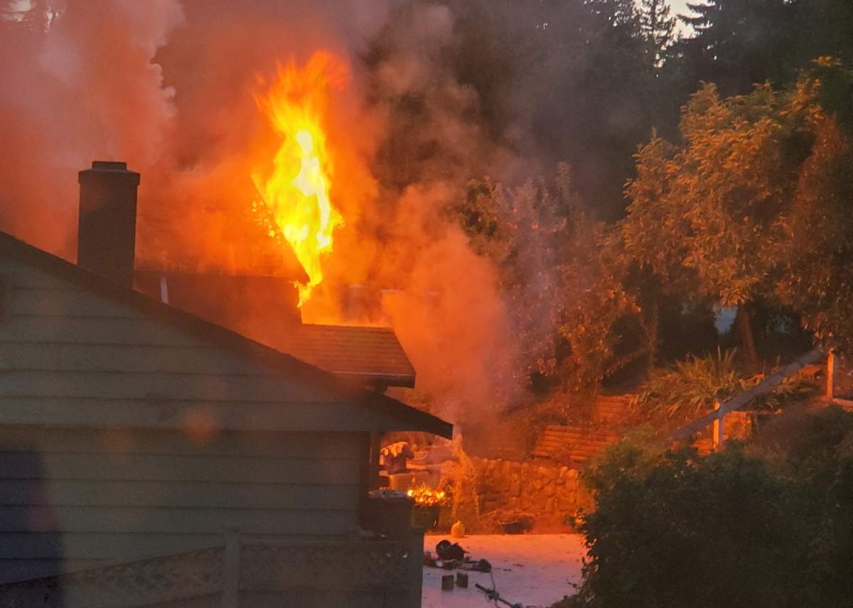 Flames shoot out of a home in Burnaby on Saturday, July 20, 2019.