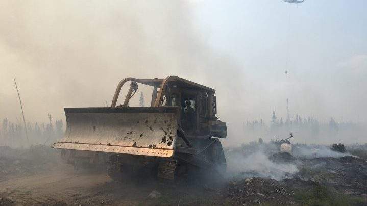 A bulldozer clears debris as crews battle a forest fire near Pikangikum First Nation, Ont. in this undated handout photo. The chief of an Ontario First Nation threatened by a forest fire says a plan to evacuate residents via buses and boats today has been paused because of a lack of space in host communities. THE CANADIAN PRESS/HO, Ontario Ministry of Natural Resources and Forestry.