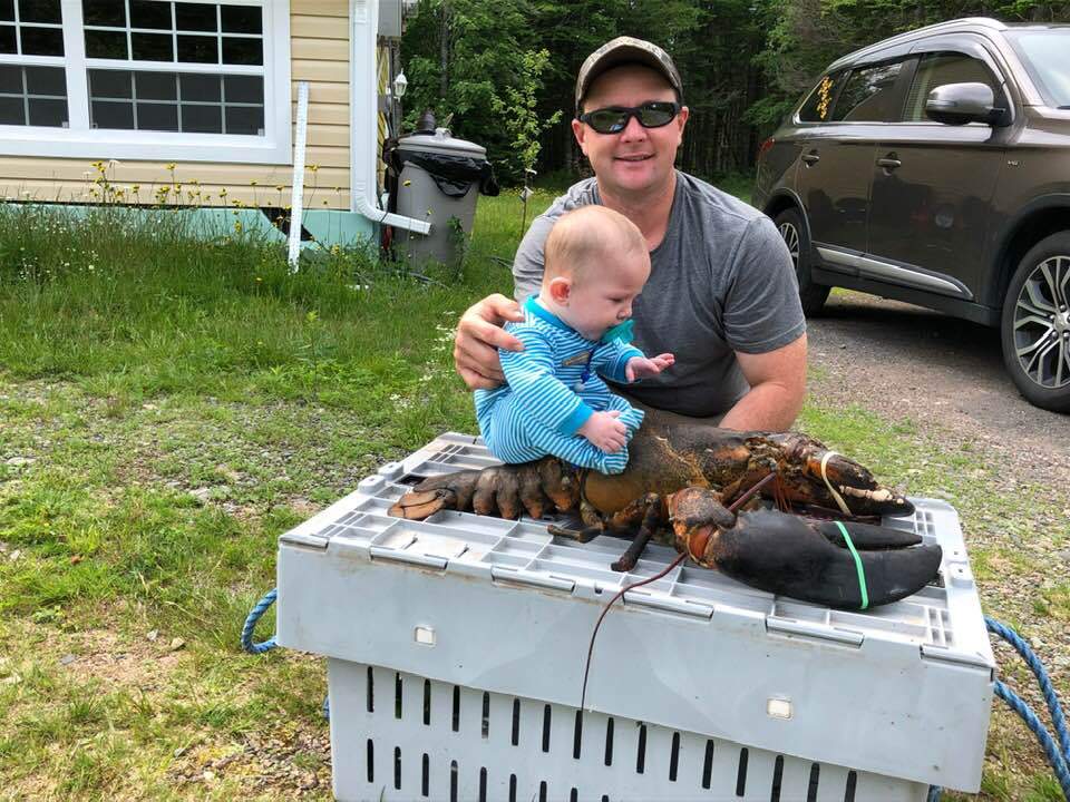 Nathan Crawford, a lobster fisherman, with his son Ace riding a lobster.
