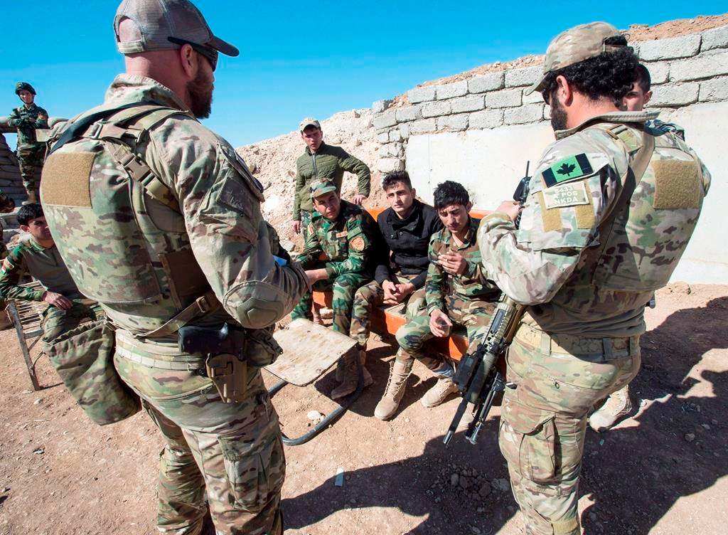 Canadian special forces soldiers, left and right, speak with Kurdish Peshmerga fighters at an observation post, in northern Iraq.