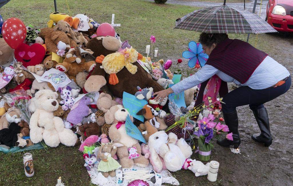 A woman places a stuffed animal in front of the house where lived a 7-year-old girl who was found in critical condition by police on Monday in Granby, Que. on Friday, May 3, 2019. PRESS/Paul Chiasson.