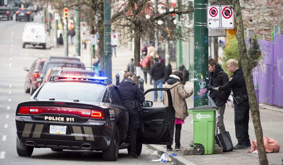 Police speak to a man and woman on East Hastings in Vancouver's downtown eastside, Thursday, Feb 7, 2019. More people fatally overdosed in British Columbia last year compared with 2017 despite efforts to combat the province's public health emergency, the coroner says. 