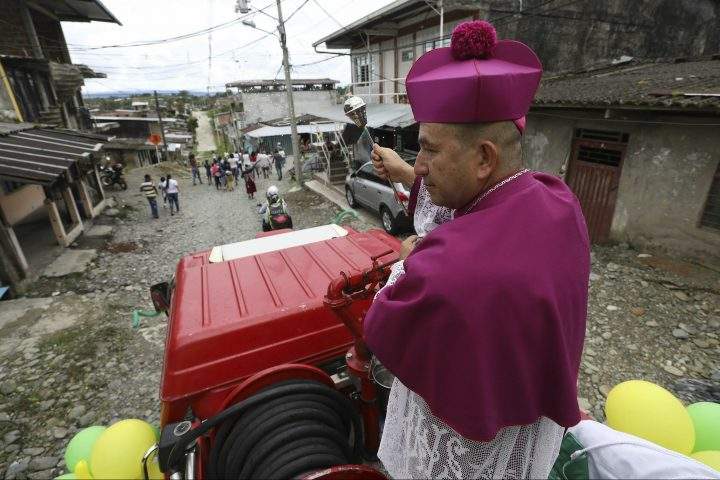 Catholic Bishop Ruben Dario Jaramillo Montoya sprinkles holy water as he travels on a fire truck through Buenaventura, Colombia, Saturday, July 13, 2019.