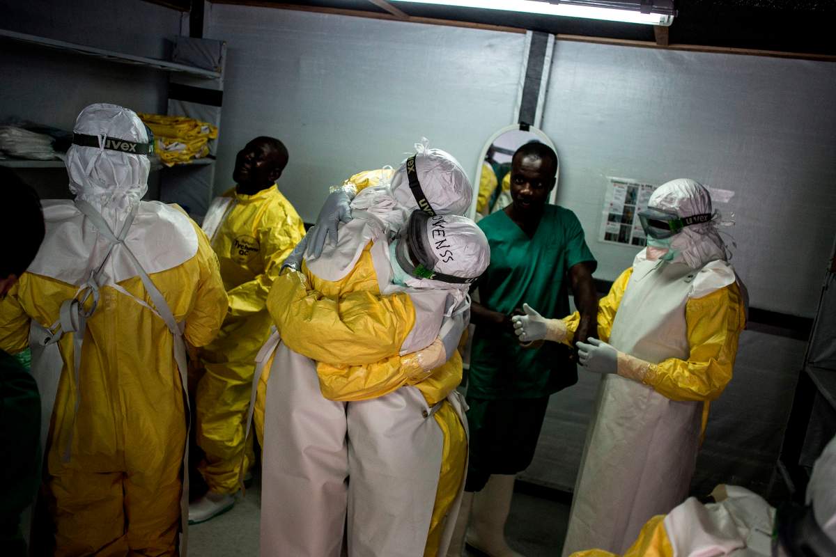 Health workers embrace whilst putting on their personal protective equipment (PPE) before heading into the red zone at a newly build MSF (Doctors Without Borders) supported ebola treatment centre (ETC) on November 7, 2018 in Bunia, Democratic Republic of the Congo.