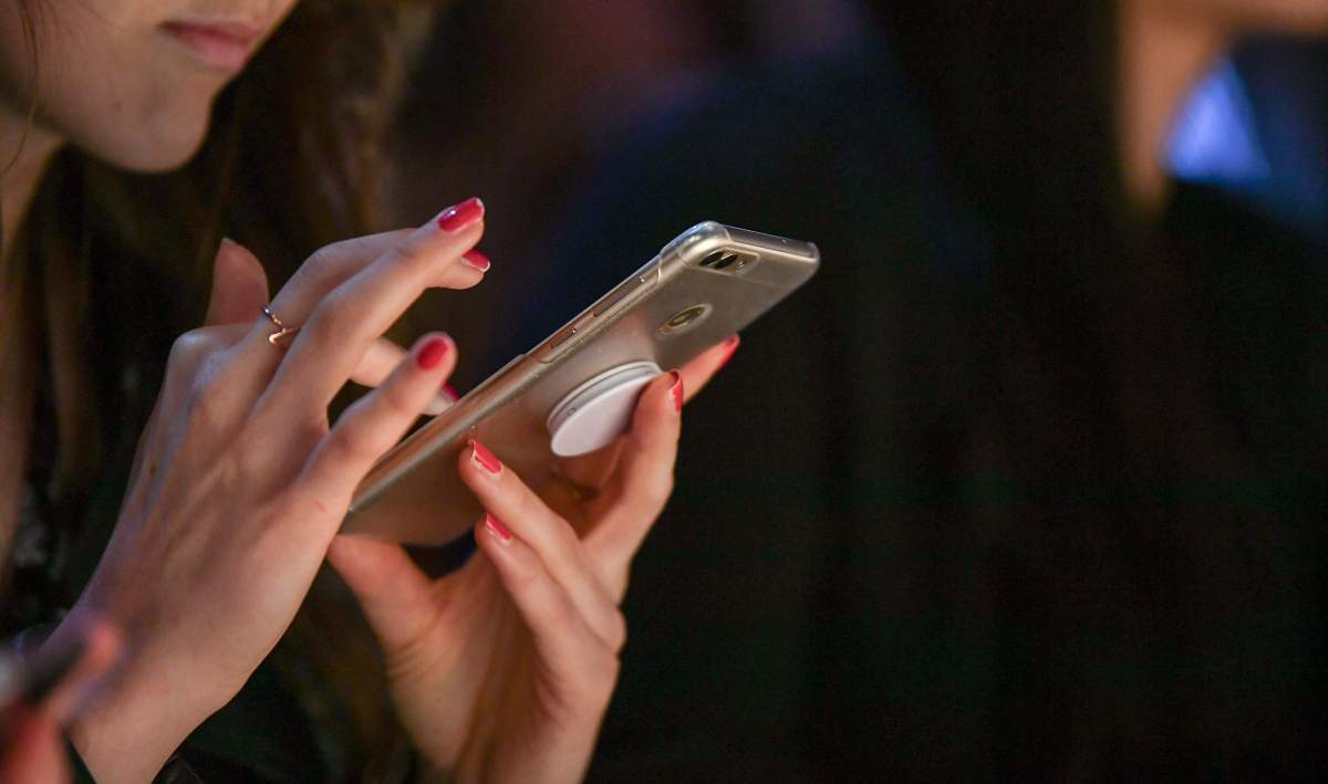  A woman is holding her smartphone in her hands during Berlin Fashion Week.