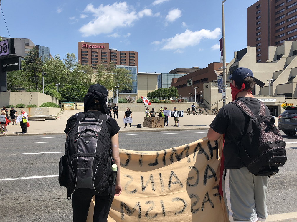 Pride supporters hold up signs across the street from Yellow Vest protesters in front of Hamilton city hall during a Pride rally earlier this month.