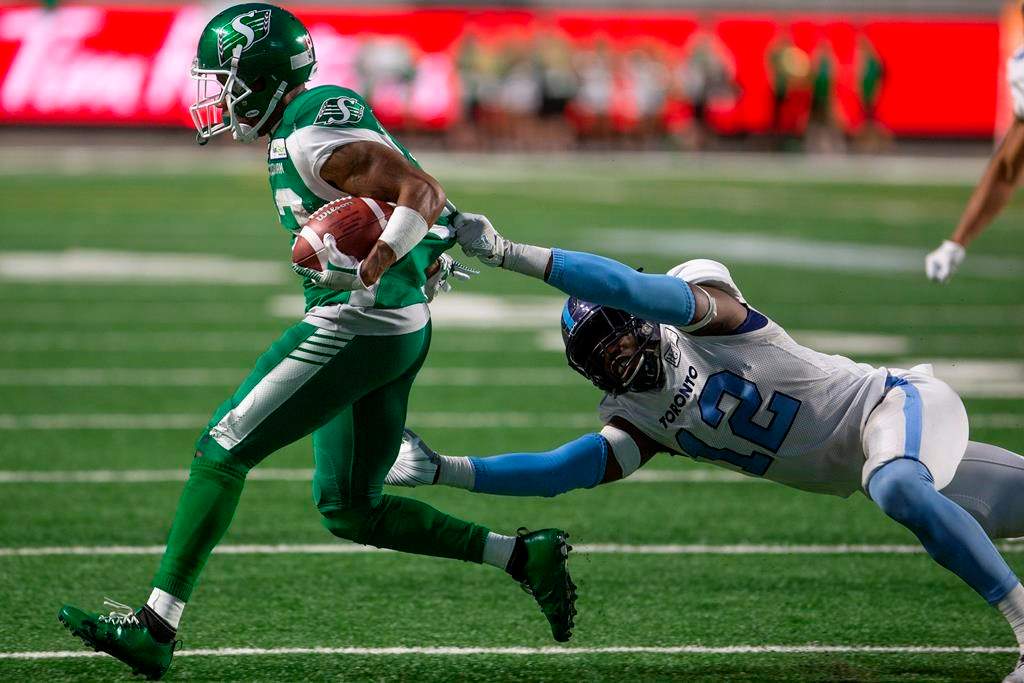 Saskatchewan Roughriders wide receiver Christion Jones (22) runs the ball as Toronto Argonauts linebacker Nelkas Kwemo (12) grabs onto his jersey during second half CFL football action in Regina on Monday, July 1, 2019.