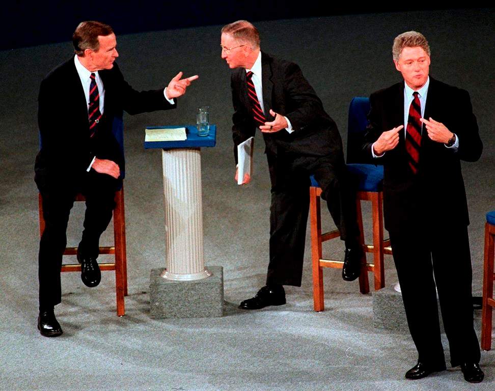 In this Oct. 15, 1992, file photo, President George H.W. Bush, left, talks with independent candidate Ross Perot as Democratic candidate Bill Clinton stands aside at the end of their second presidential debate in Richmond, Va. (AP Photo/Marcy Nighswander, File)
