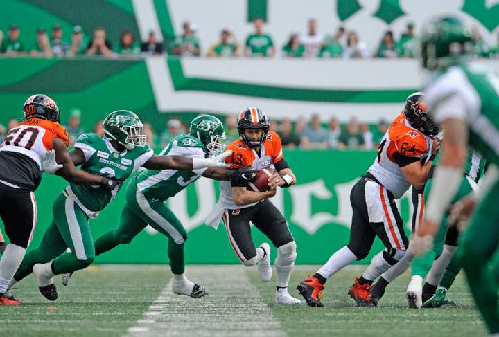 B.C. Lions QB Mike Reilly runs the ball under pressure from Saskatchewan Roughriders defenders at Mosaic Stadium on July 20, 2019.
