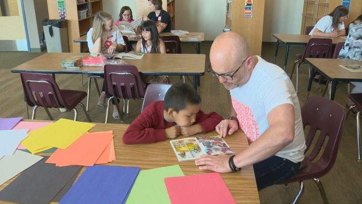 United Way Saskatoon CEO Shaun Dyer reading to a Summer Success student.