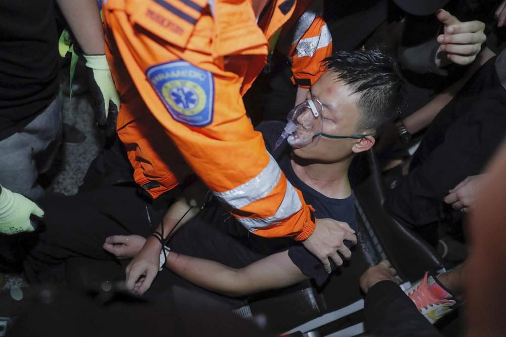 A medical staffer helps a detained man, who protesters claimed was a police officer from mainland China, during a demonstration at the Airport in Hong Kong, Tuesday, Aug. 13, 2019.