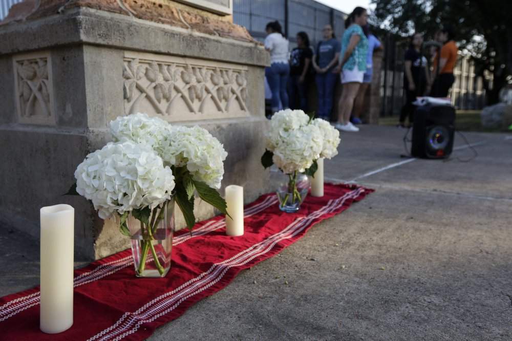 An altar of candles and white hydrangea flowers stands in memoriam of the 22 victims of the recent El Paso shooting during a vigil Sunday, Aug. 11, 2019, at Alice Wilson Hope Park in Brownsville, Texas.